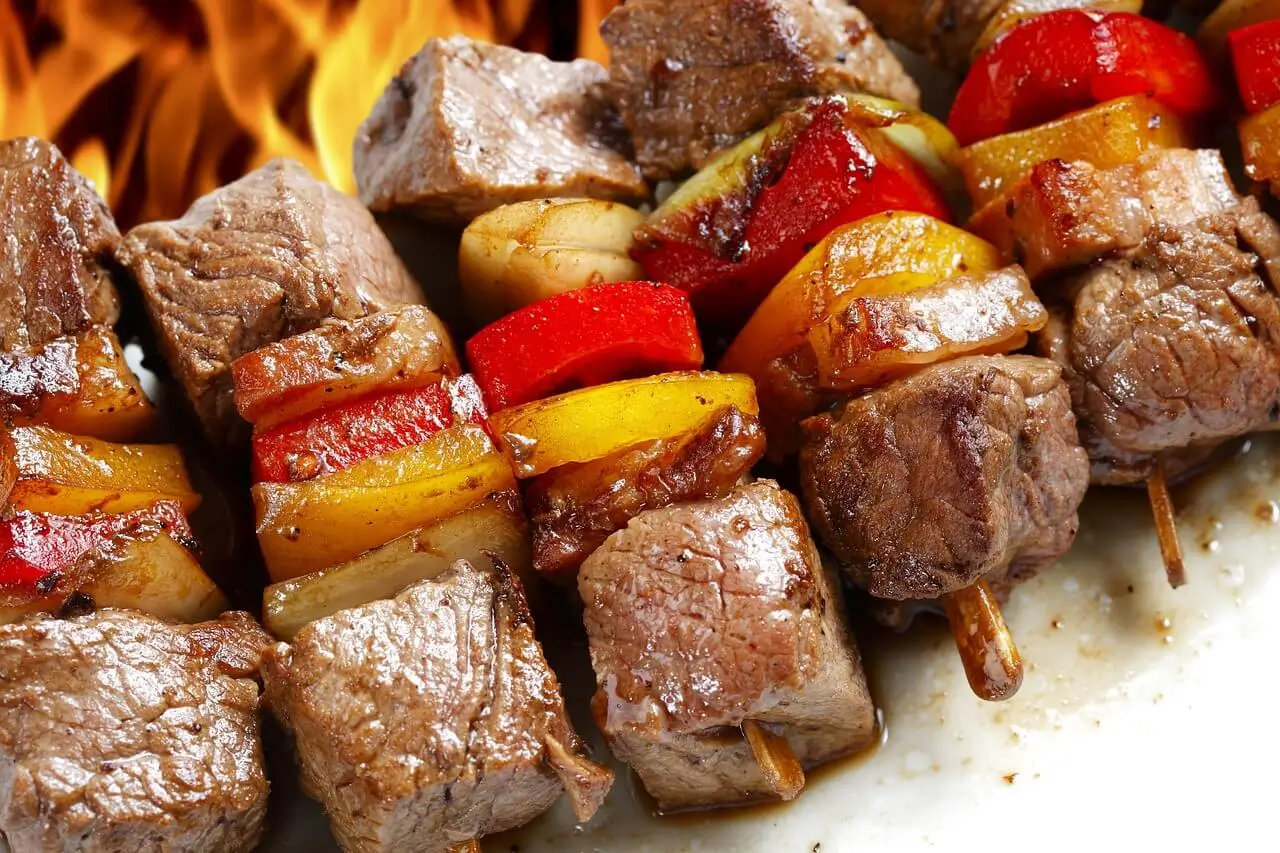 "Grilled beef heart kebabs skewered with colorful vegetables, sizzling on the grill."