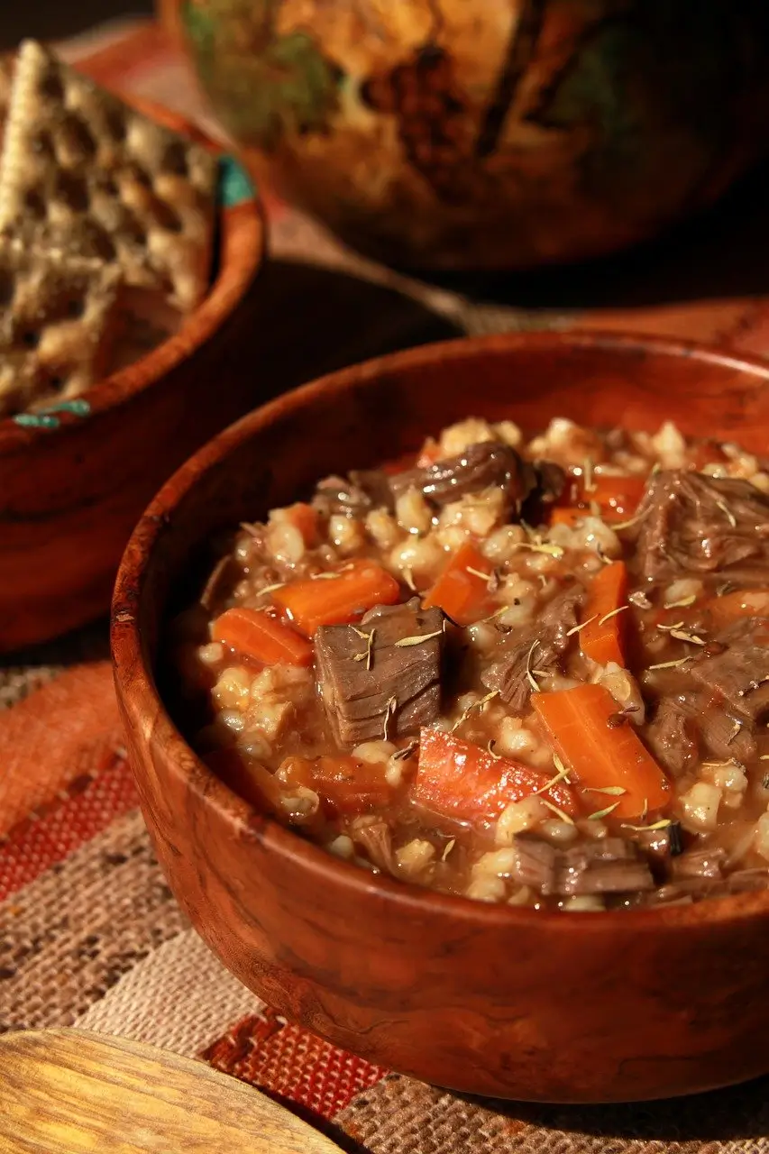 "A bubbling beef heart pot stew filled with carrots, potatoes, and herbs, served in a rustic bowl."