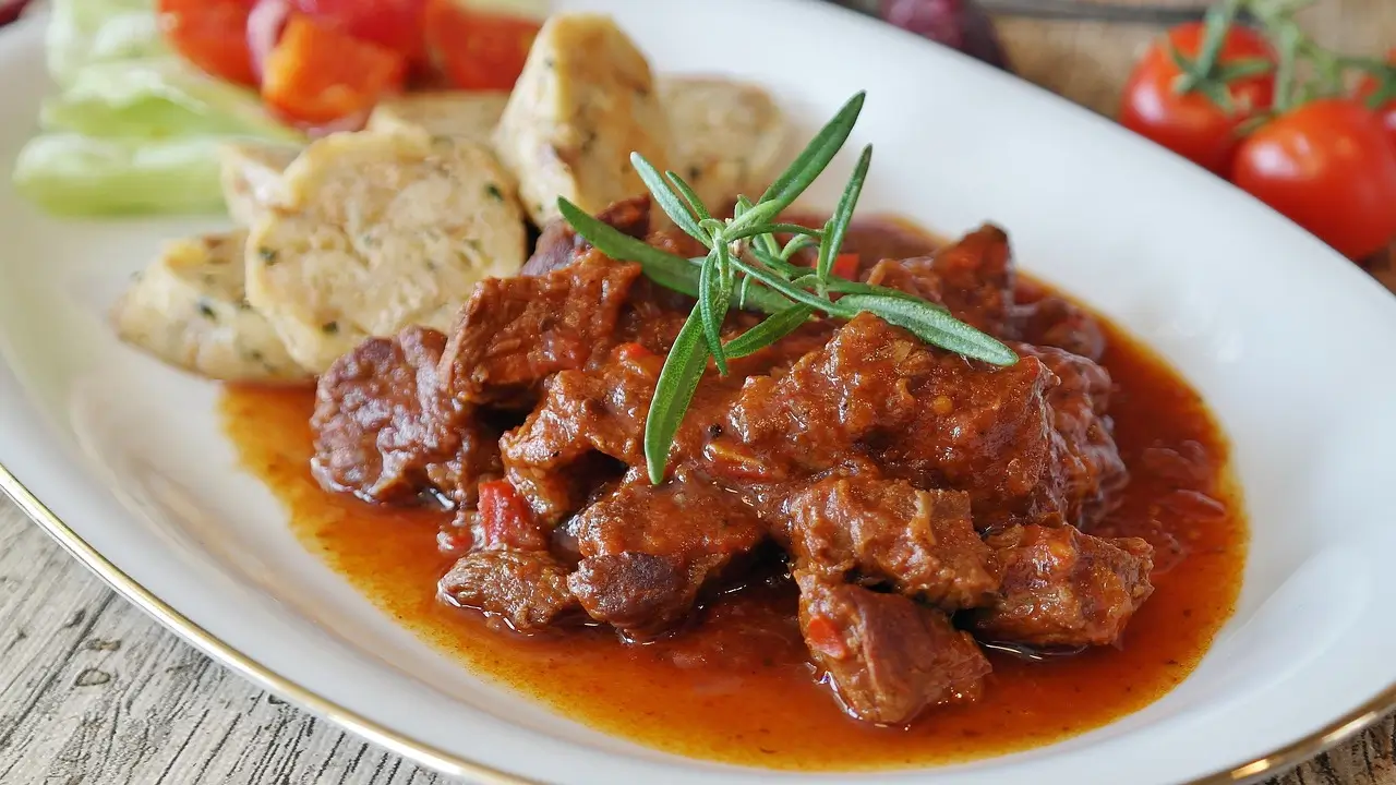 "A hearty beef heart pot stew simmering in a cast iron pot, filled with vegetables and spices."